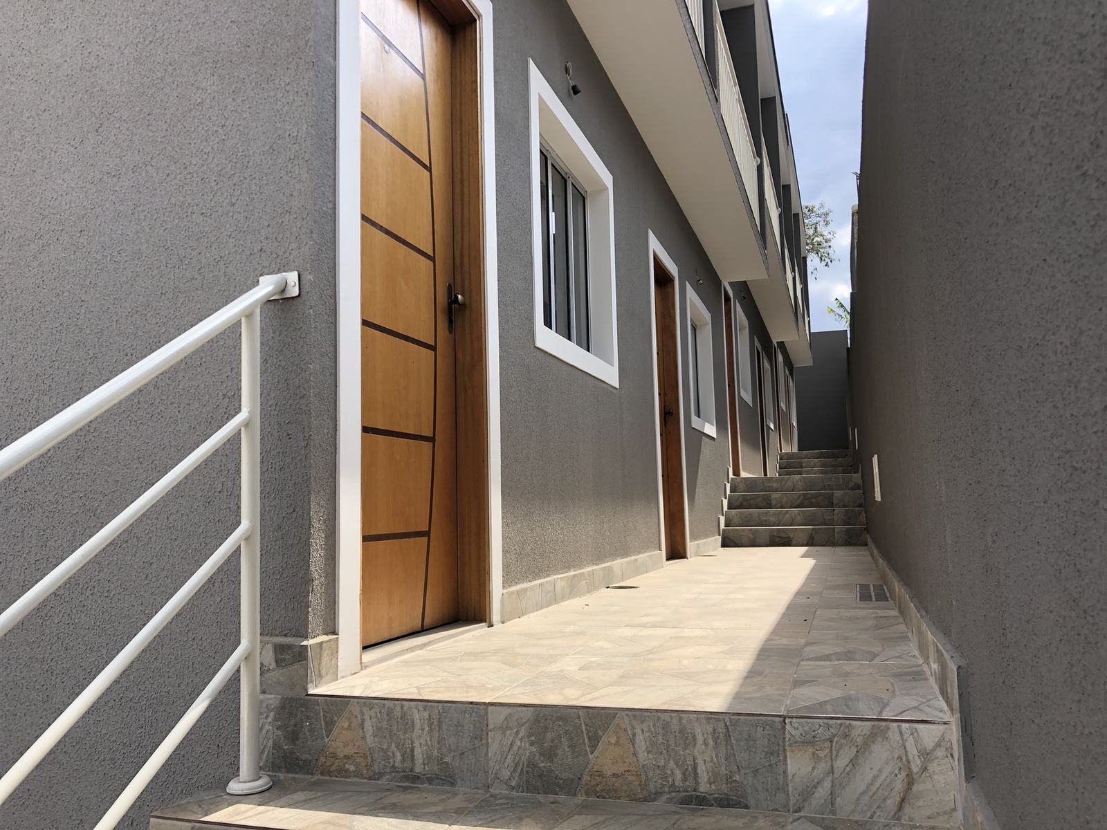 Fachada do sobrado com corredor de acesso às unidades, em Cotia
